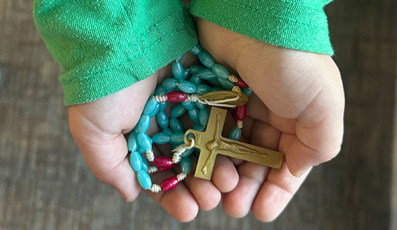 Child's hands holding a rosary