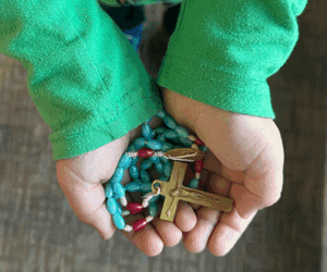 Child's hands holding a rosary