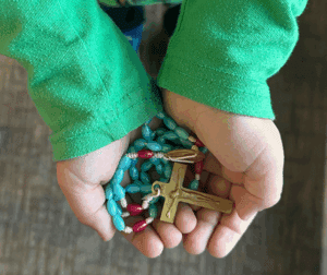 Child's hands holding a rosary