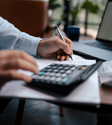 person writing and typing on calculator